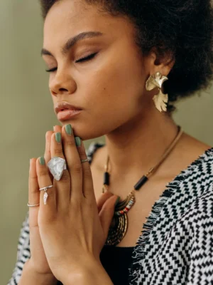 A woman with crystal accessories meditates, embodying calmness and spiritual focus.